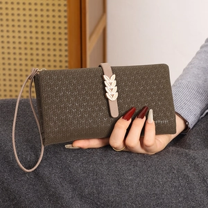 Close-up of a brown leaf wallet showing the knitting pattern texture and golden metal buckle