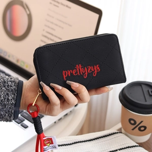 Close-up of black quilted PU leather wallet with zipper and red woven wristlet strap
