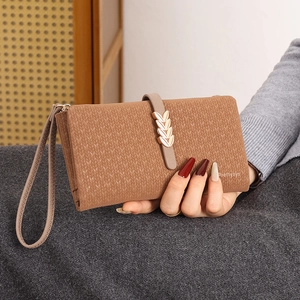 Detail of caramel brown wallet with leaf buckle, knit texture, and wrist strap