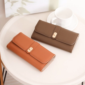 Detail of long leather wallets in orange and brown with gold metal twist locks