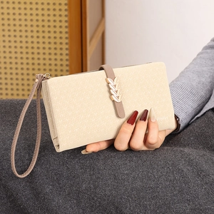 Detail of apricot matte leather wallet featuring gold leaf buckle and zipper wrist strap
