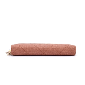 Macro detail of brown woven leather texture and metal zipper pull on long wallet