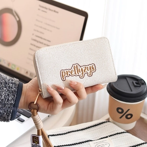 Close-up of beige quilted PU leather wallet with brand embroidery and wrist strap