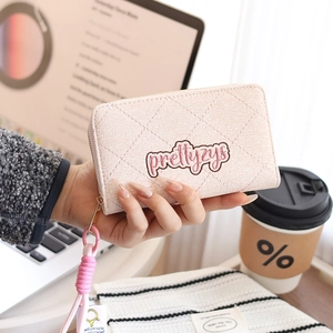 Detailed view of light pink quilted card holder with zip closure and wrist strap