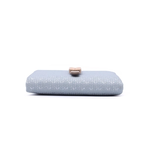 Detail of light blue textured wallet featuring a leaf-shaped gold metal clasp closure