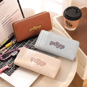 Detailed view of quilted long wallets in caramel, blue, and pink with hand straps