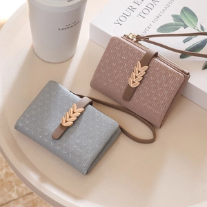 Close-up of textured leather wallets with golden leaf clasps and wrist straps