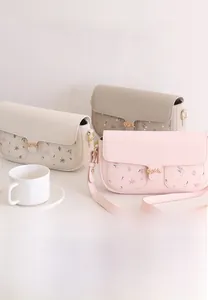 Chic women's crossbody bag featuring floral patchwork detail and a gold leaf clasp
