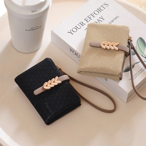 Close-up of black and beige short wallets with gold leaf buckles and wrist straps