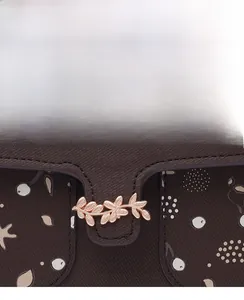 Close-up of textured leather handbag with rose gold leaf buckle and abstract art print