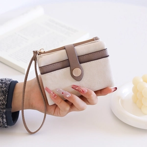Detail of beige and brown leather wallet featuring card slots and a wristlet strap