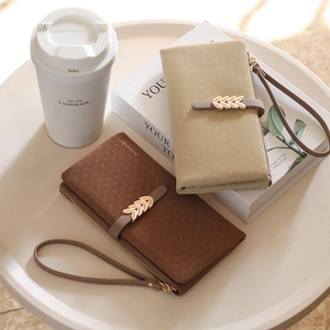 Detailed view of leather texture and gold leaf buckle on beige and brown wallets