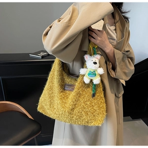 Detail of yellow fuzzy hobo bag with teddy bear pendant and fashion leather label