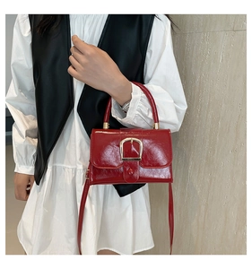 Detail of red glossy vintage handbag with gold horseshoe buckle on elegant model