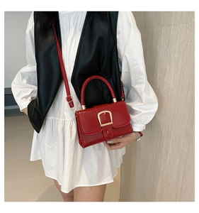 Macro shot of red patent leather square handbag featuring a golden U-shaped metal buckle