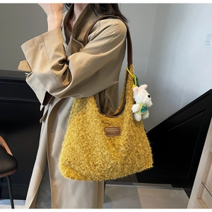 Detail of yellow plush tote with brown leather strap and white puppy plush charm