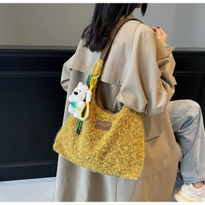 Detail of yellow plush tote bag with brown leather strap and white bear charm