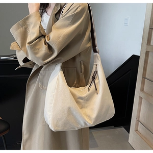 Detail van de minimalistische crème canvas tas met brede bruine riem en ritssluiting