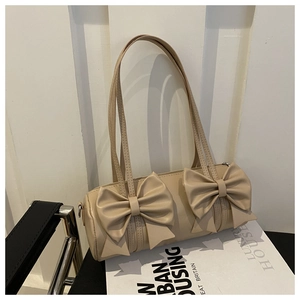 Détail du sac cylindre beige avec doubles nœuds géants et texture fine en similicuir