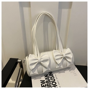 Détail du sac polochon blanc orné de deux grands nœuds et de clips en métal argenté