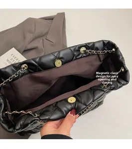 Detailed view of the magnetic closure and gold chain on this black quilted shoulder bag