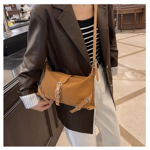 Brown vintage faux leather shoulder bag with adjustable buckles worn by model in cafe