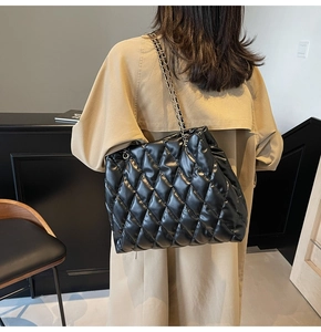 Detail of black quilted leather shoulder bag with woven chain strap and large capacity
