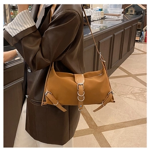 Detailed shot of brown faux leather shoulder bag with decorative metal buckle and ring