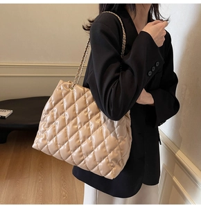Close-up of beige quilted shoulder bag featuring gold chain strap and elegant stitching