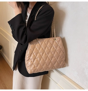 Detail of beige quilted shoulder bag with gold chain strap and elegant faux leather texture