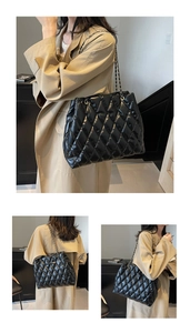 Detail of black quilted leather tote bag with metal chain strap and sleek glossy finish