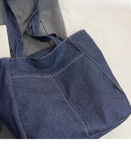 Detail of dark blue denim tote bag showing contrast stitching and premium denim texture