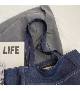 Detail of dark blue denim tote bag shoulder strap with reinforced contrast yellow stitching