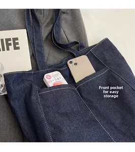 Detail of blue denim tote bag featuring a practical front pocket for small item storage