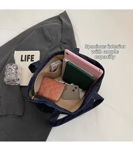 Top view of spacious denim tote interior holding a tablet, wallet, and daily essentials