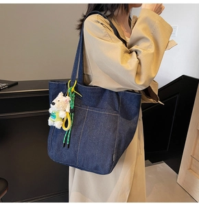 Detail of dark blue denim tote bag with contrast stitching and plush puppy pendant