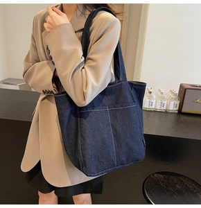 Detail view of deep blue denim tote bag with contrast stitching on a modern indoor setting