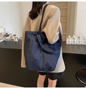 Close-up of a large denim tote bag with contrast stitching in a cozy cafe setting