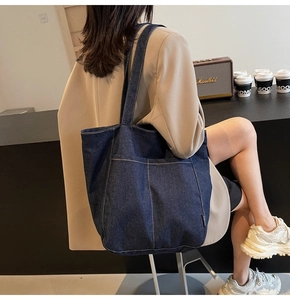 Detail view of deep blue denim tote bag with large front pockets and contrast stitching