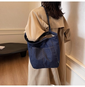Macro shot of dark blue denim tote bag featuring white stitching and fashion label detail