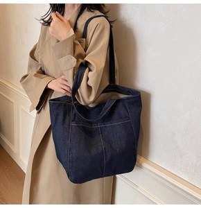 Blue denim tote bag styled with a beige trench coat for a casual autumn look
