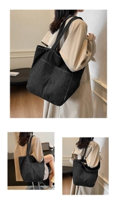 Close-up of black denim tote bag with white contrast stitching and outer pockets
