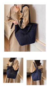 Detail of dark blue denim tote bag with yellow stitching shown on model's shoulder
