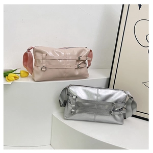 Pink and silver patent leather crossbody tote bag with wide strap on a white stand