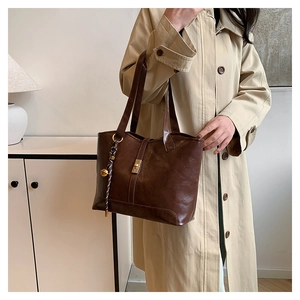 Quilted tote bag in dark brown leather with gold hardware shown with trench coat