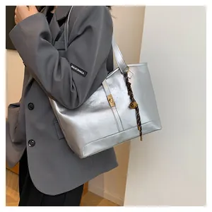 Close-up of silver metallic tote bag featuring a golden lock and woven bell charm