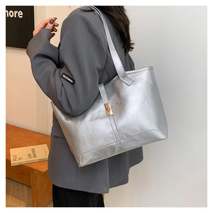 Side view of silver tote bag featuring metallic quilted texture and golden buckle