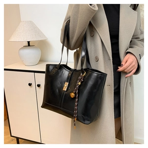 Close-up of black quilted tote bag with golden twist-lock and decorative brown charm