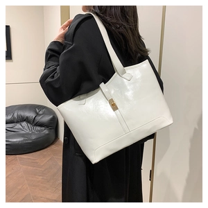 White glossy leather tote bag with gold buckle clasp on model for daily commuting
