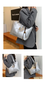 Detail of silver metallic tote bag featuring a gold twist lock and woven charm strap